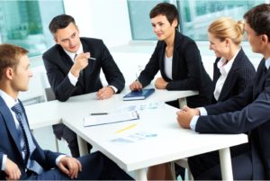 Four business professionals discussing documents in a meeting room.